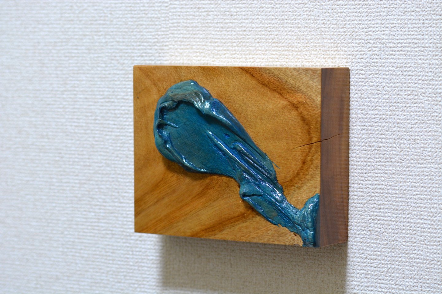 Scultura di una conchiglia blu applicata su un pannello di legno