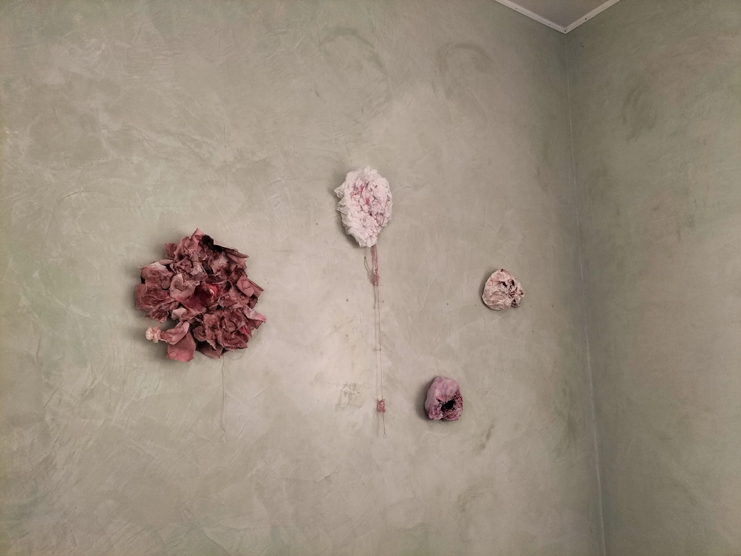 Quattro sculture di carta colorata attaccate a una parete di colore chiaro, disposte in modo casuale.