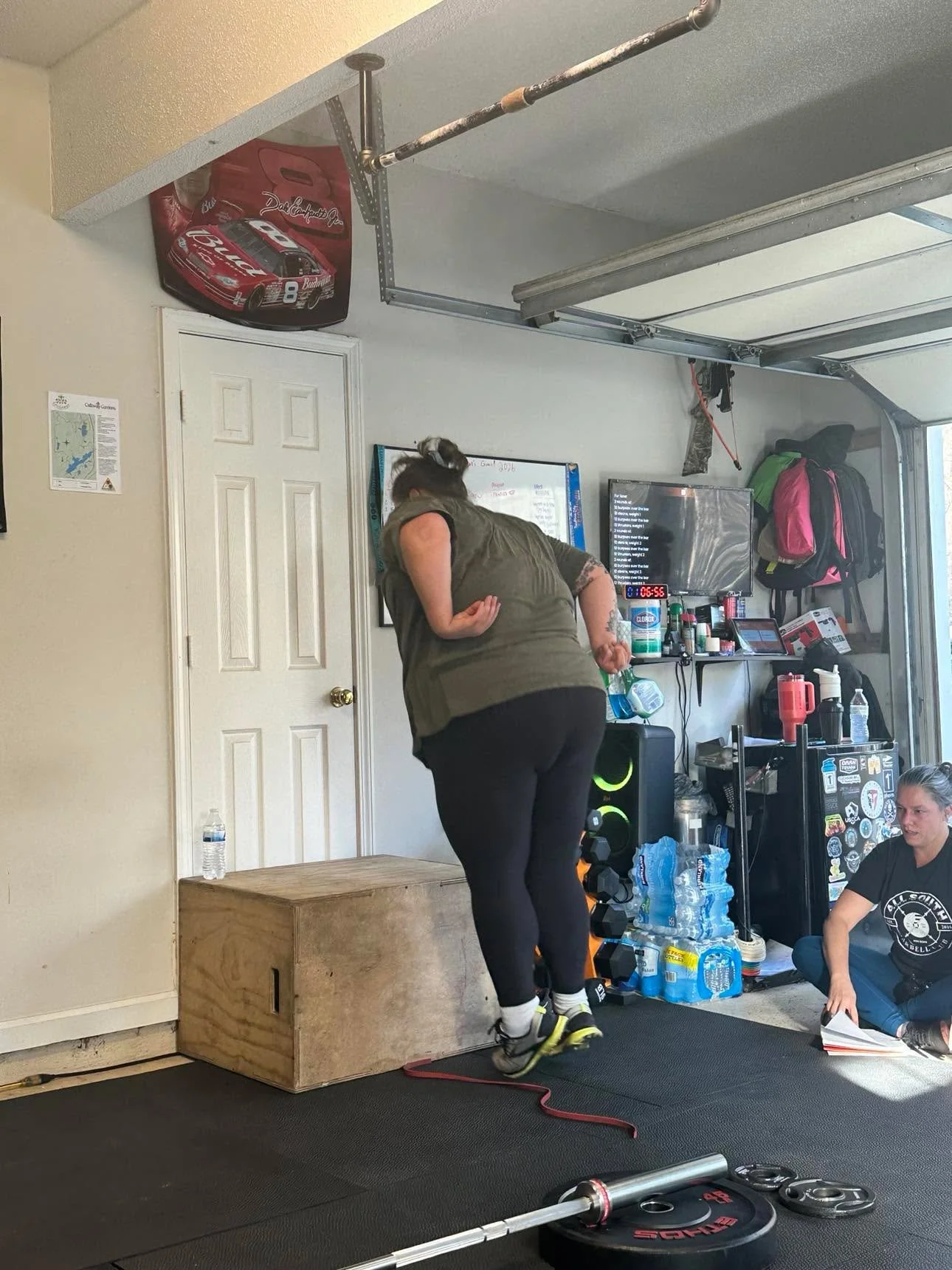 Woman jumping onto a wooden box in a garage gym.