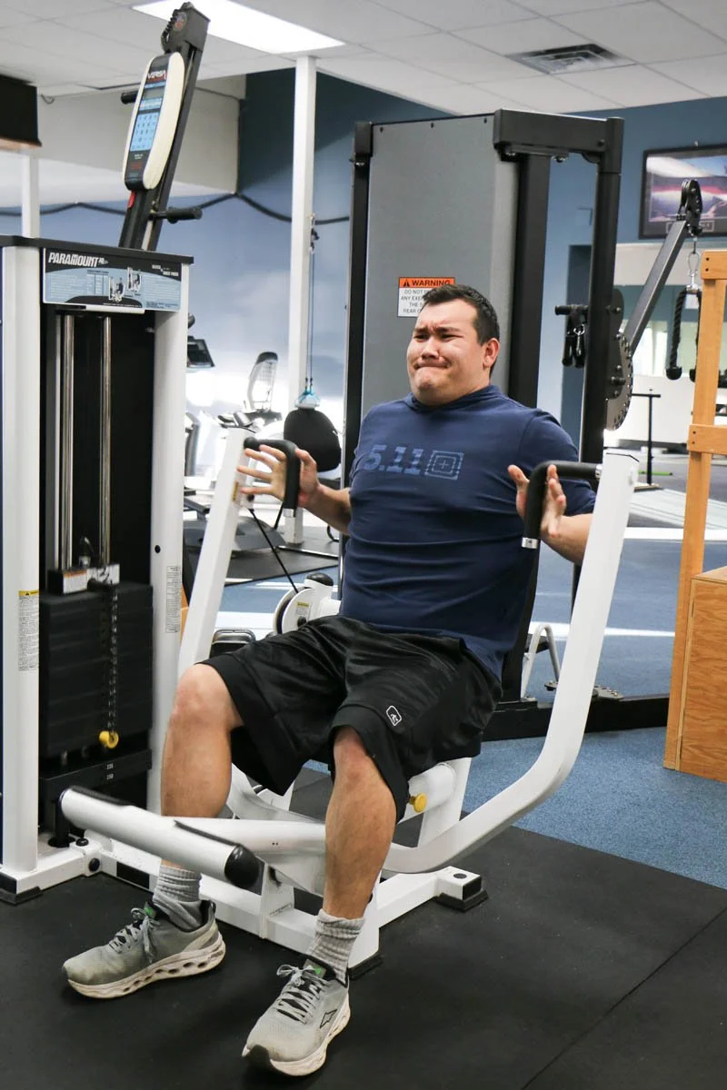 A man exercising with a seated row machine in a gym.