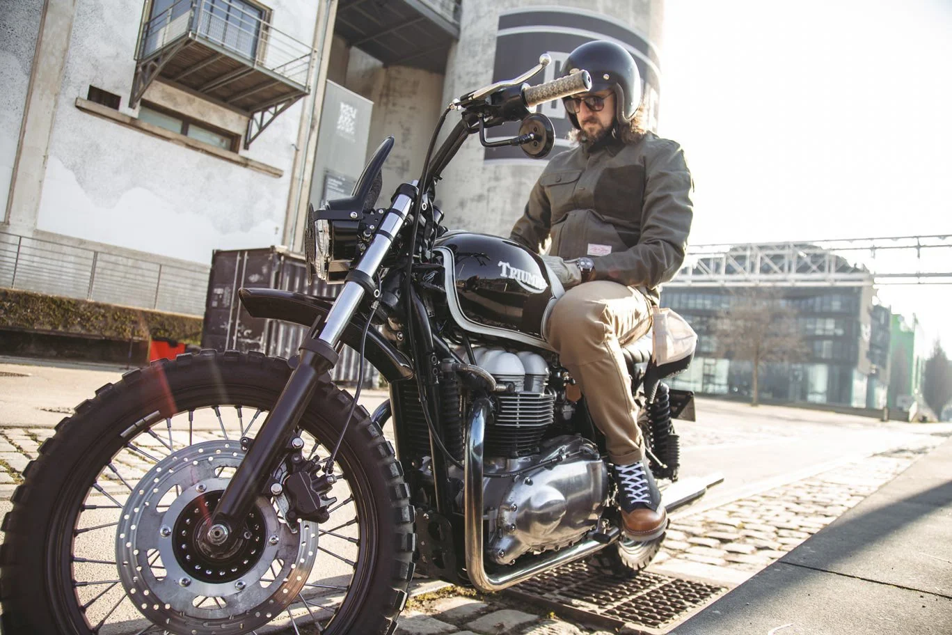 Photo of a man wearing Age of Glory clothing whilst sitting on a street scrambler type bike