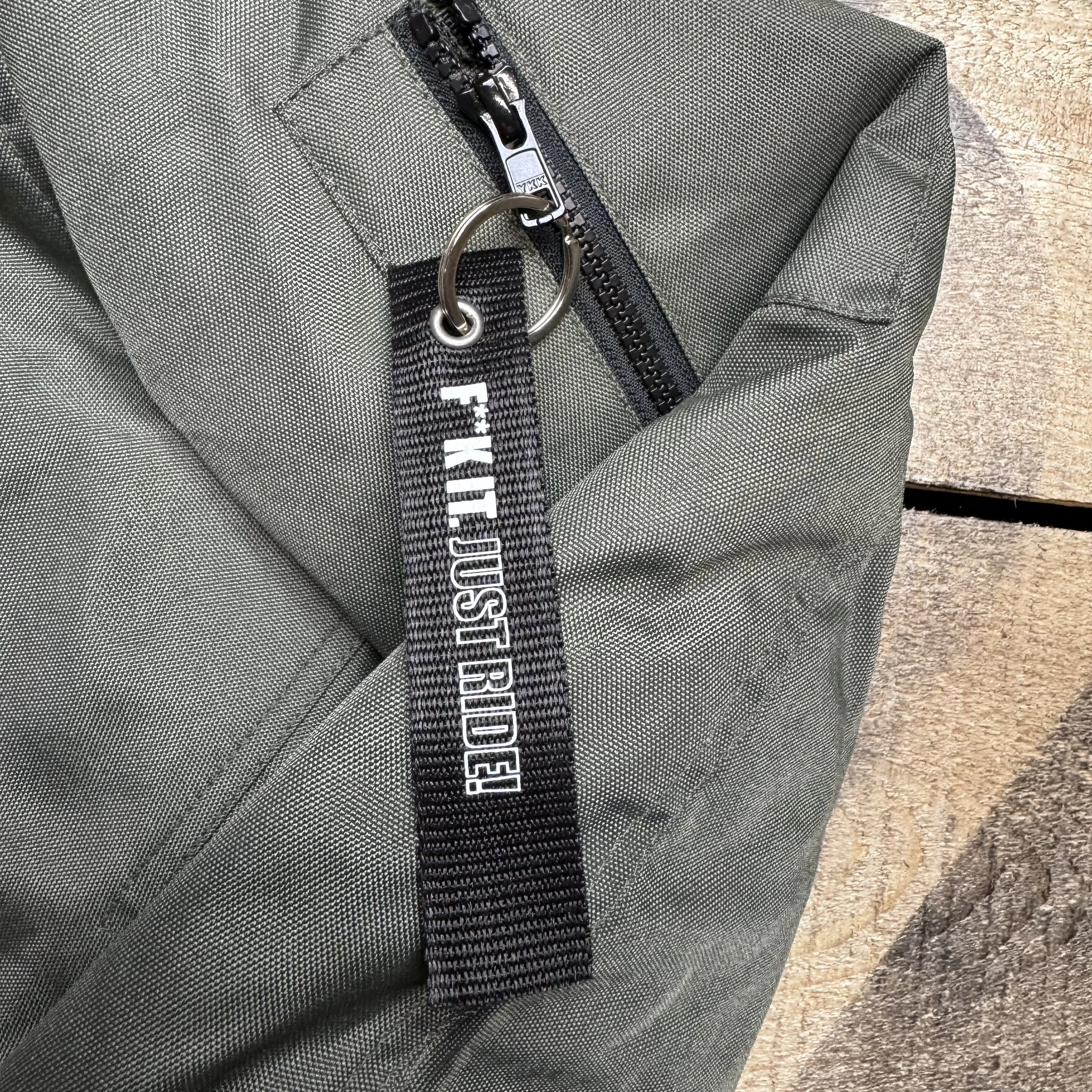 Close-up photo of the 'remove before flight style' zipper tag on a BOBHEAD bomber jacket