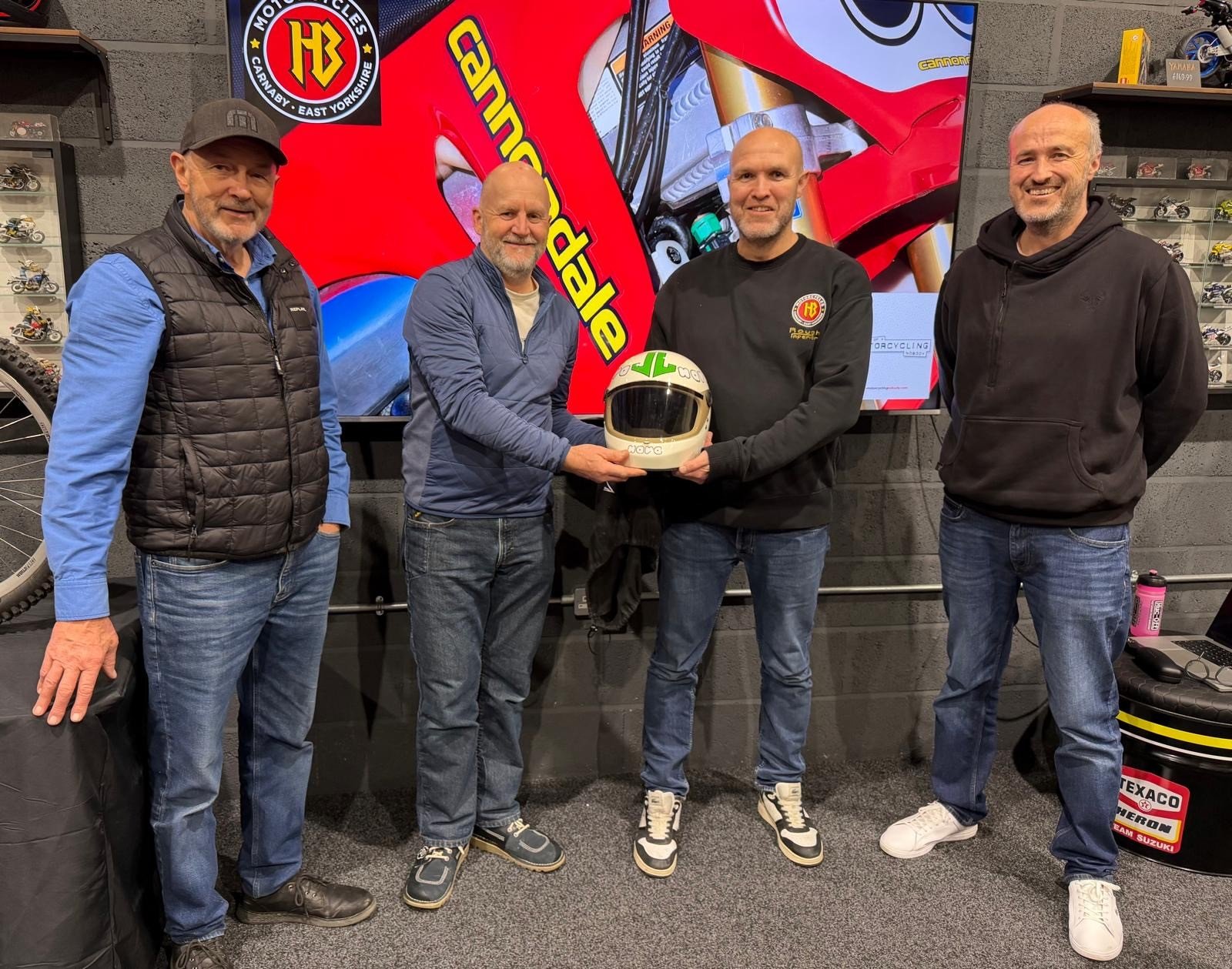 Photo of Guy Redshaw presenting a Mick Grant replica crash helmet to HB Motorcycles staff