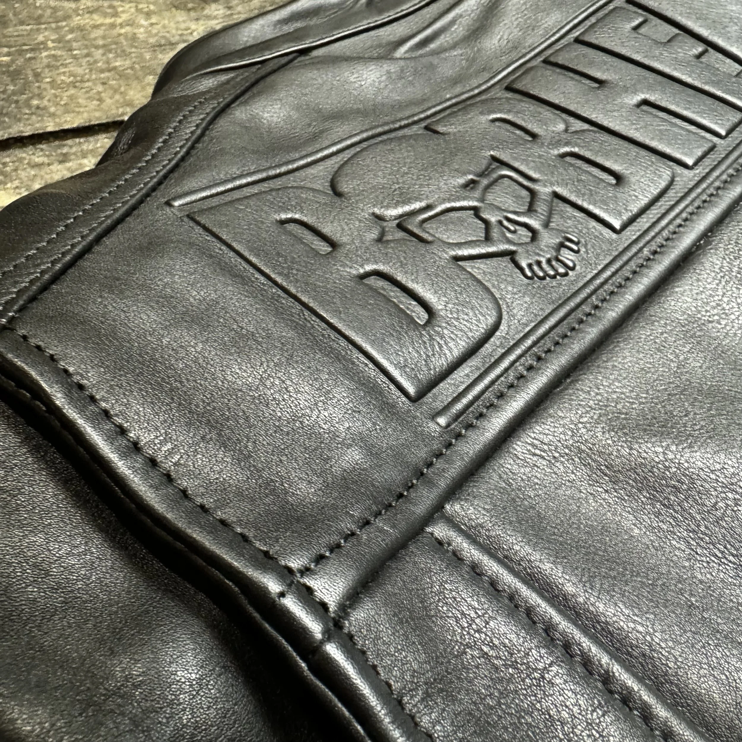 Close-up photo of the BOBHEAD logo embossed on the back of a black leather jacket