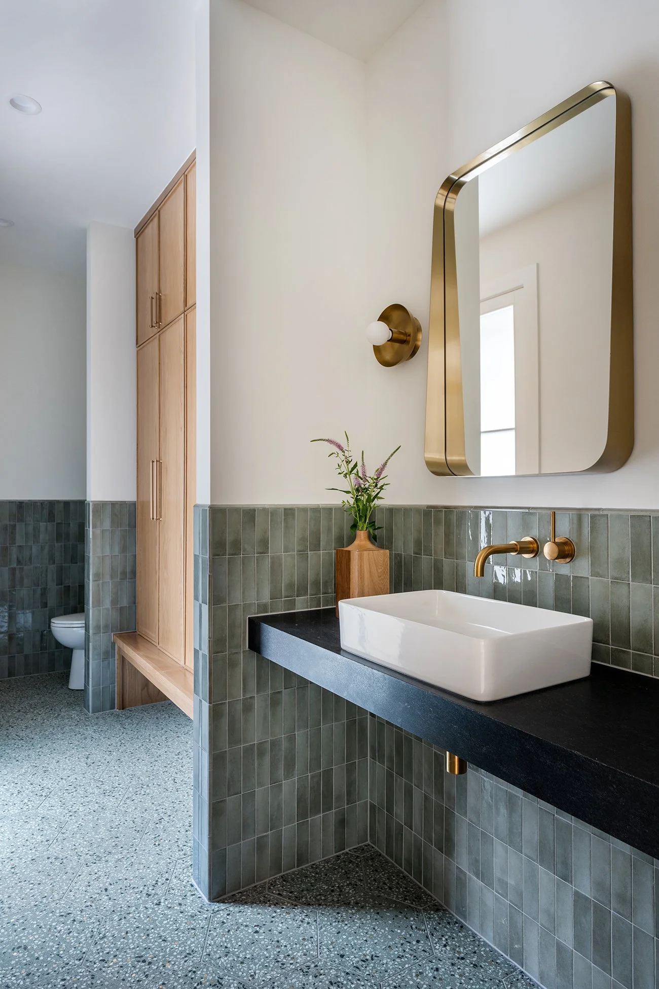 Modern bathroom with floating stone vanity, brass mirror and warm modern finishes in a Northwest Hills Austin home by Christen Ales Interiors.