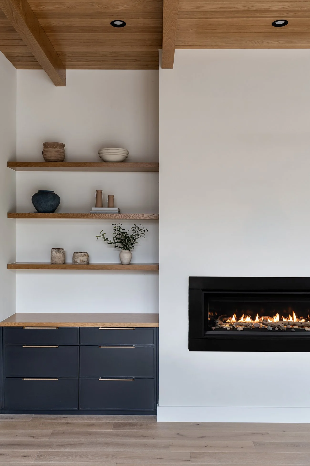 Custom dark cabinetry with natural wood shelving and modern fireplace in a Northwest Hills Austin home by Christen Ales Interiors.