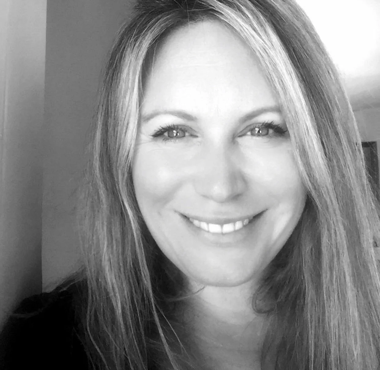 Black and white portrait of smiling woman with long hair.