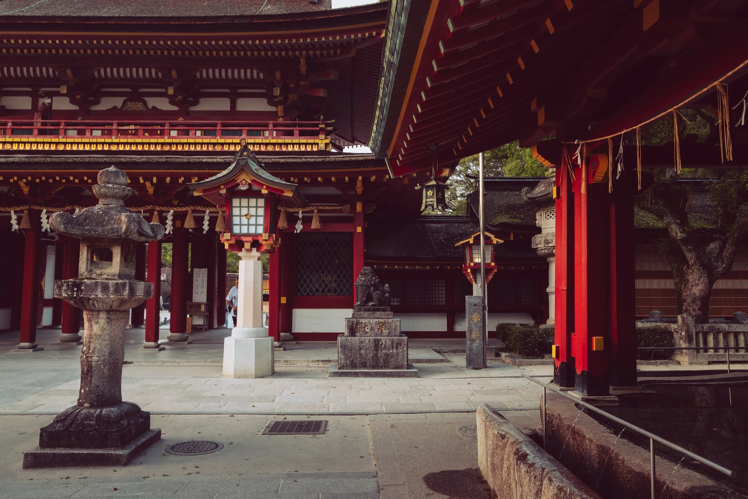 Traditional Japanese shrine with stone lanterns and red wooden structures.
