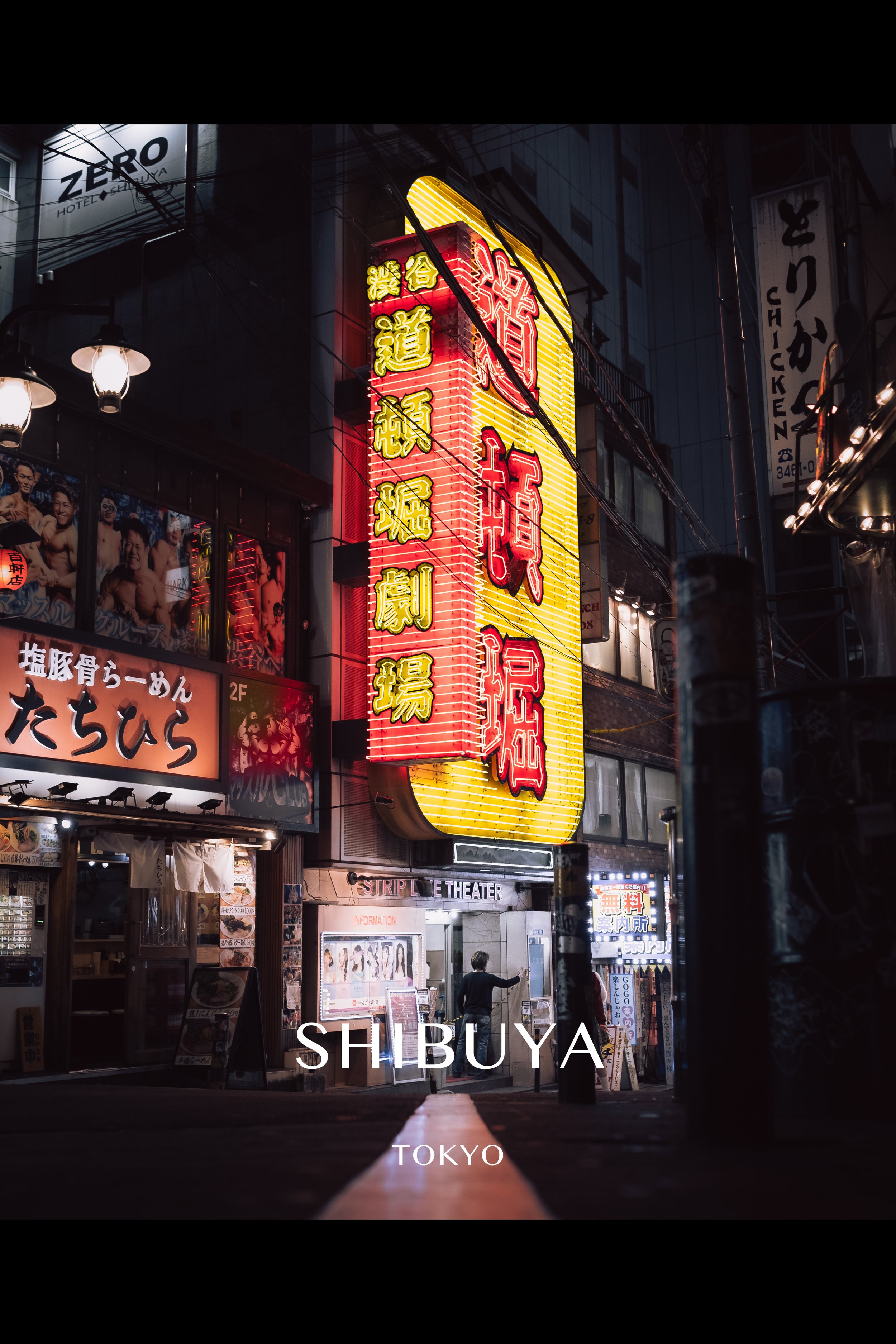 Night street scene in Shibuya, Tokyo with bright neon signs in Japanese and a person walking by.
