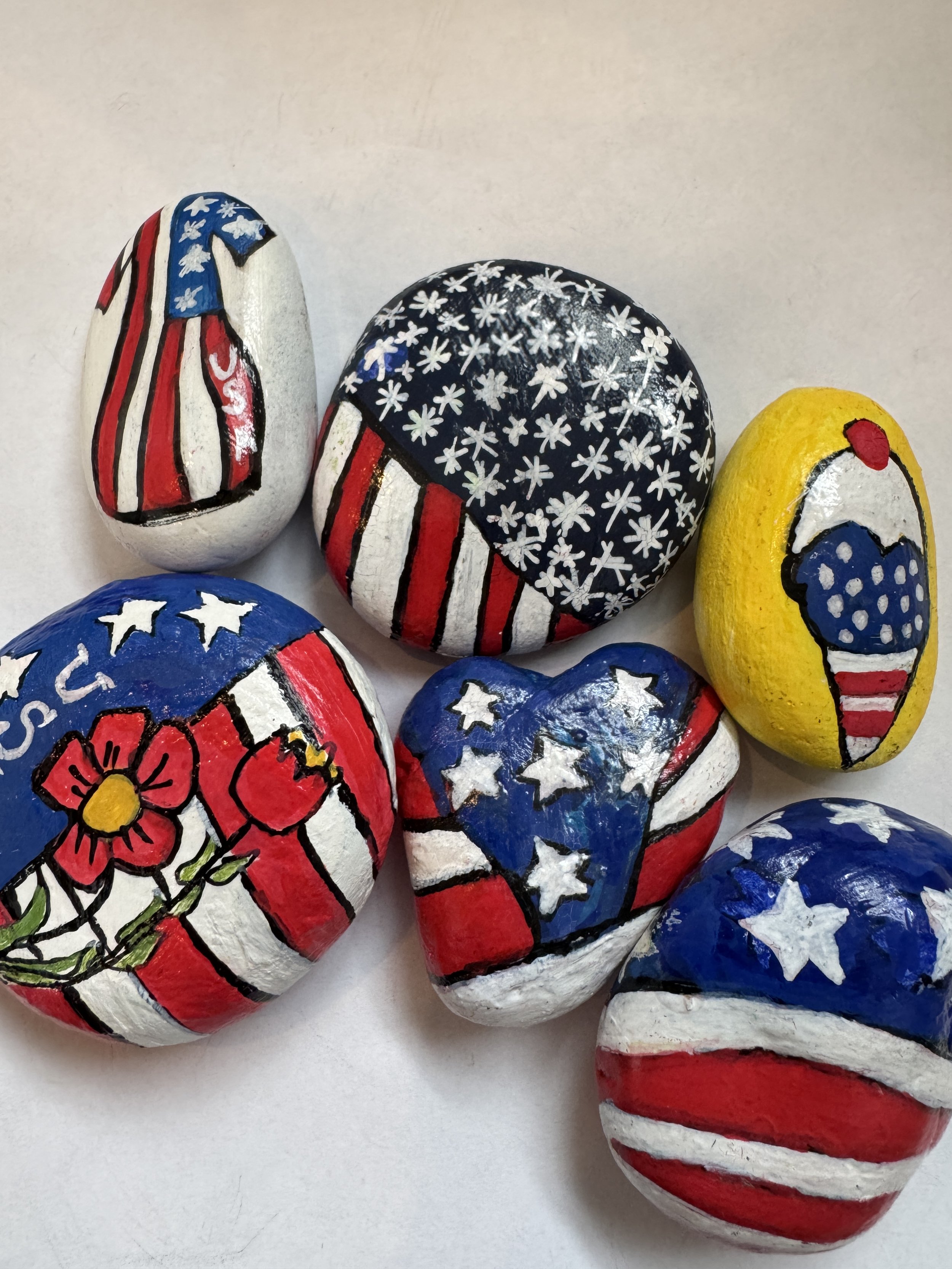 Painted rocks with American flag and patriotic themes.