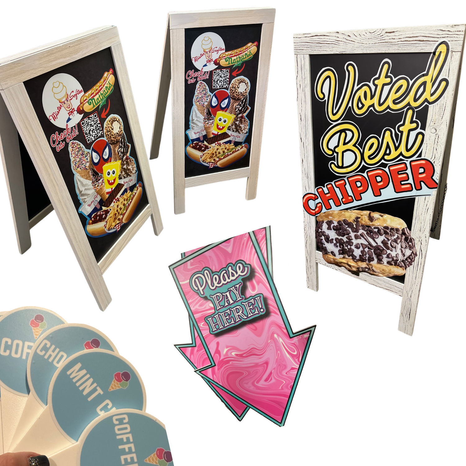 Three A-frame chalkboard signs displaying ice cream and dessert images, a pink arrow sign that says 'Please Pay Here!', and a partial view of waffle cone signs with flavors like 'Choco Mint' and 'Coffee'.