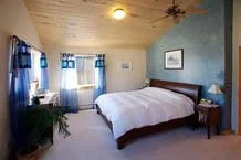 Bedroom with a bed, nightstand, and window with blue curtains.