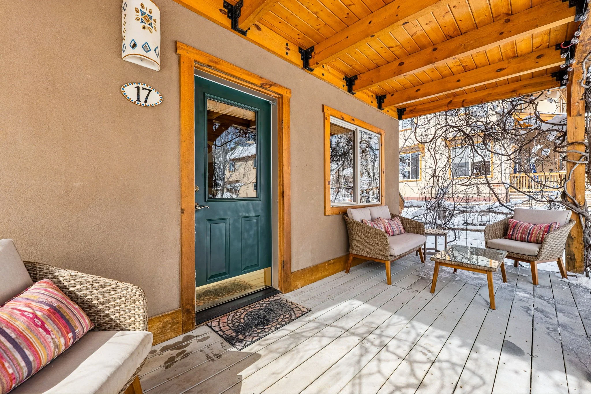 Front porch with outdoor seating, wooden ceiling, and snowy landscape.