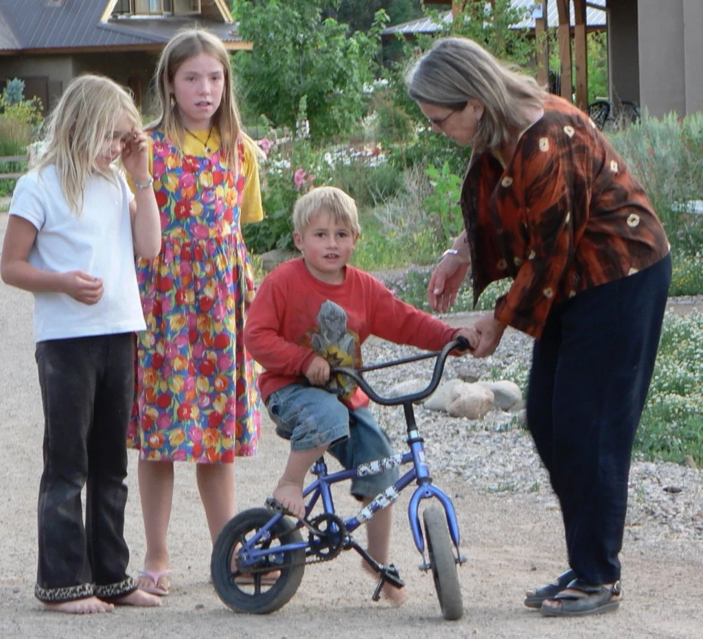 Mimi helping Joe learn to ride a bike. An extended family environment means loving, caring adults in every home.