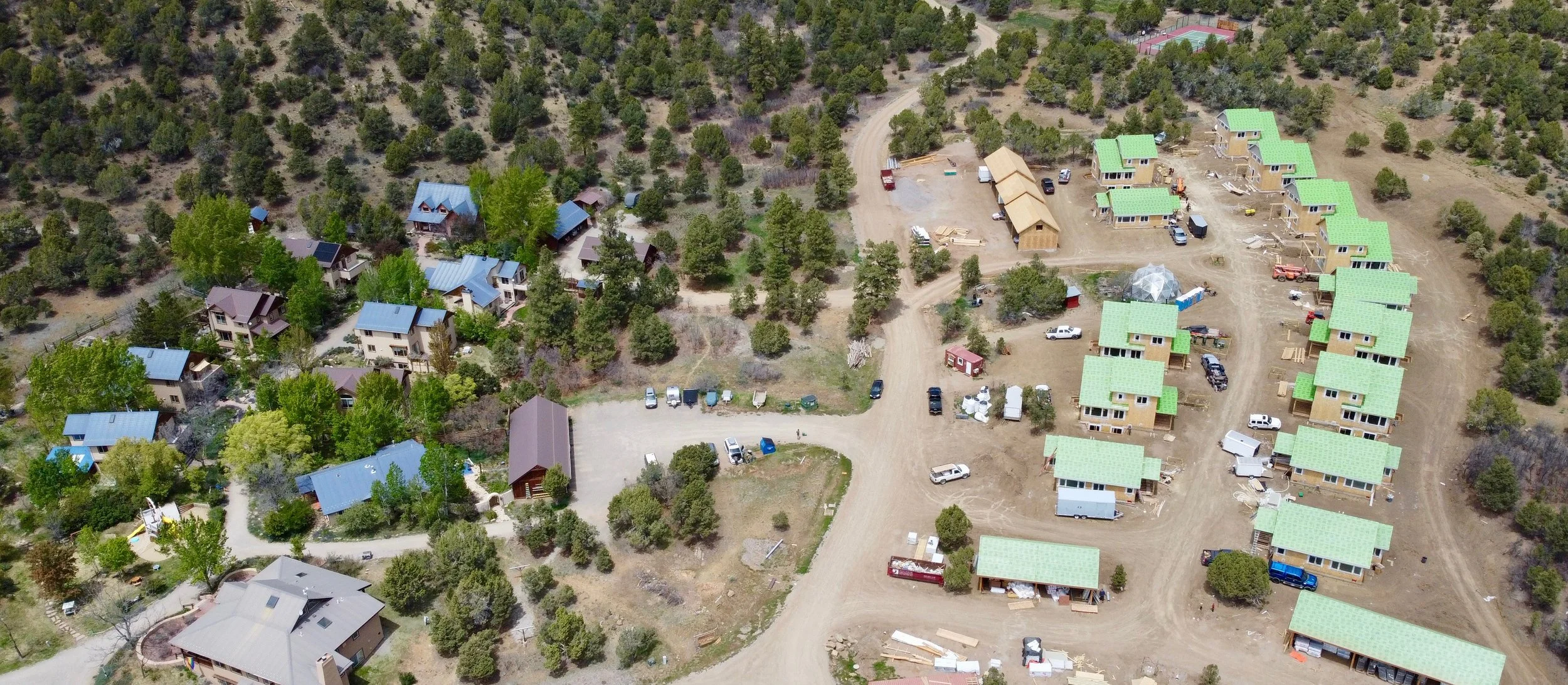 Existing housing cluster on the left and 14 new super energy efficient homes (with temporary with green roofs) and a geodesic dome greenhouse and tennis and pickleball court on the right.