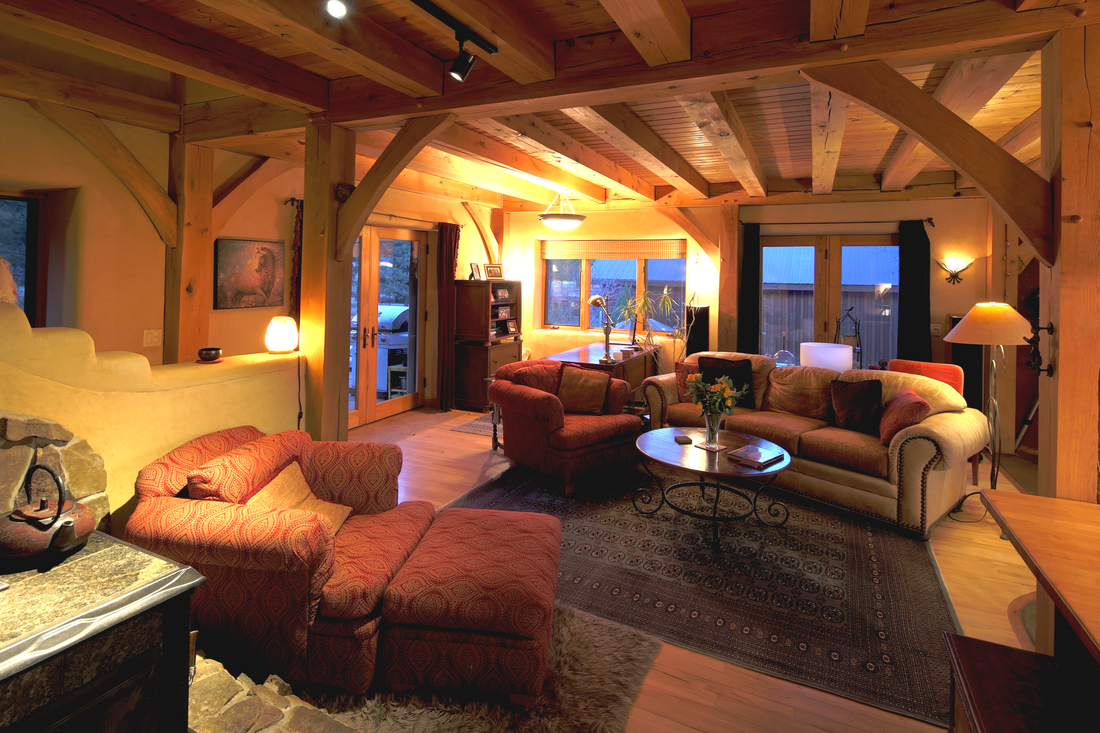 Cozy living room with wood beams, multiple couches, a coffee table, and warm lighting.