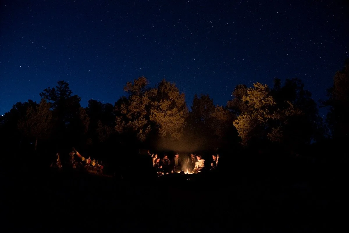 Gathering around the fire under a dark, starry sky.