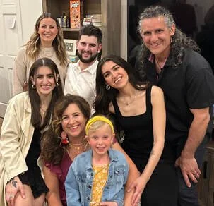 Group of seven people, including five adults and two children, smiling indoors.