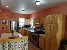 Kitchen with wooden cabinets, stainless steel refrigerator, and a gas stove, decorated with a bowl of flowers on an island.