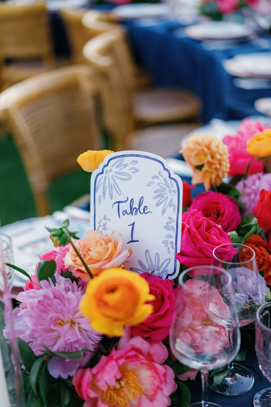 Table 1 decorated with colorful pink, yellow, and peach flowers, and a white table sign with purple text and floral illustrations.