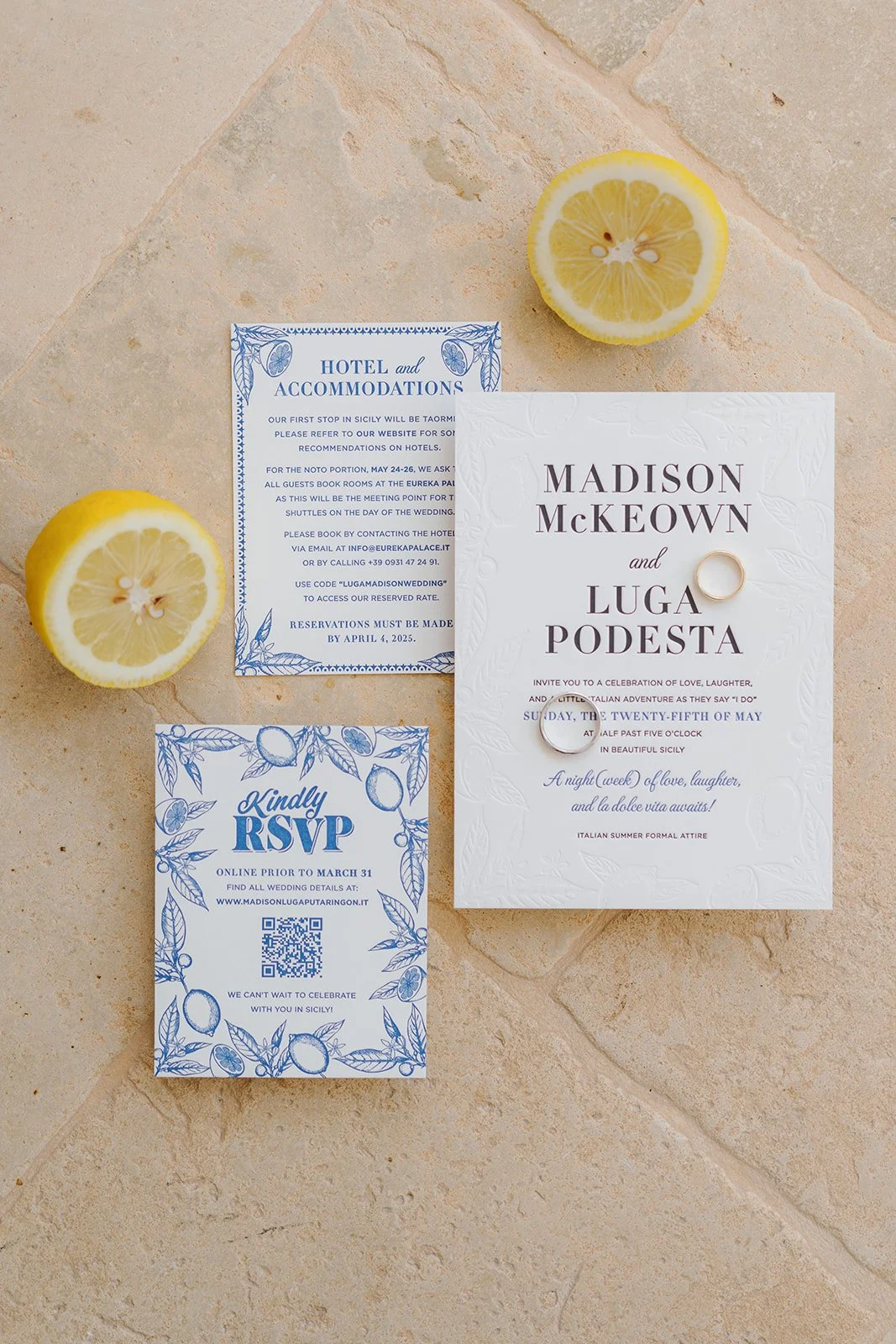 Wedding invitation suite with two rings on a white card, RSVP card, and a hotel information card, placed on a beige tiled surface with two lemon halves nearby.