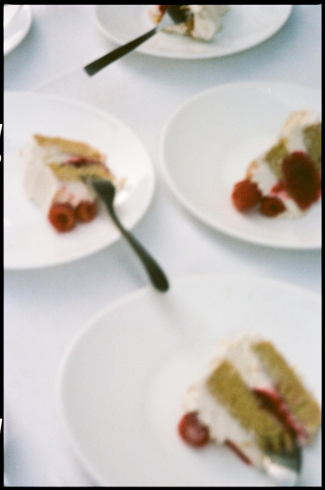 Slices of cake with cream and berries on white plates.