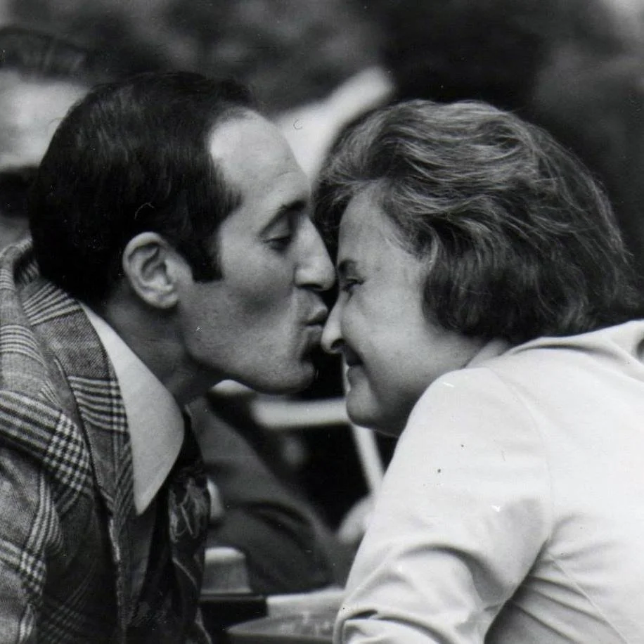 A man and a woman sharing a kiss, eyes closed, in a close, intimate moment.
