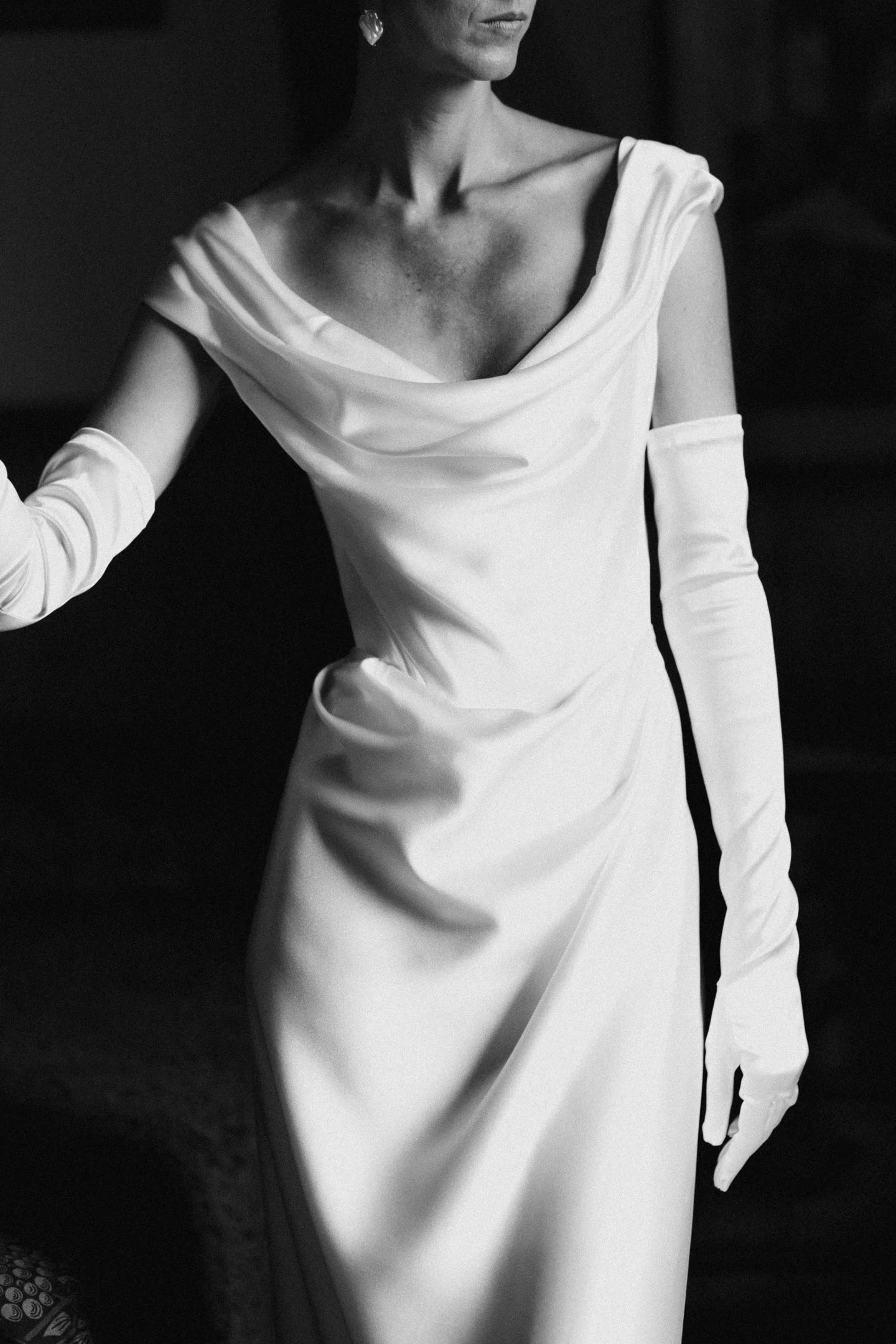 A woman wearing a long white dress with long gloves, captured in black and white.