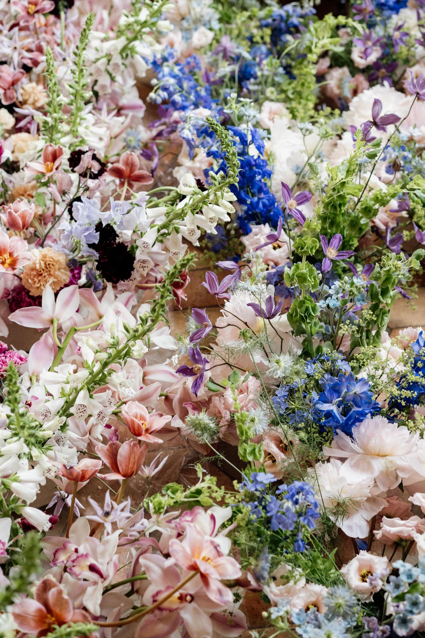 A colorful assortment of various flowers including pink, purple, blue, white, and peach blooms arranged together.