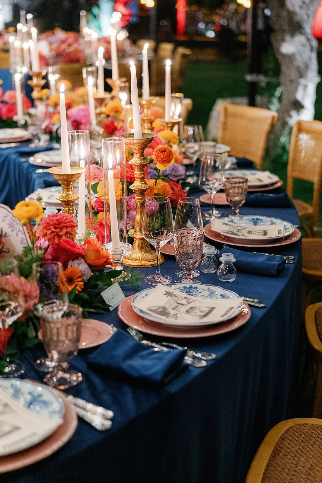 A decorated dining table with candles, flowers, plates, glassware, and utensils for a formal event.