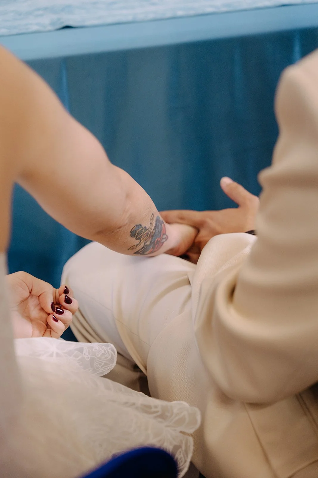 Close-up of a couple holding hands during a wedding ceremony, with the bride and groom sitting close together.