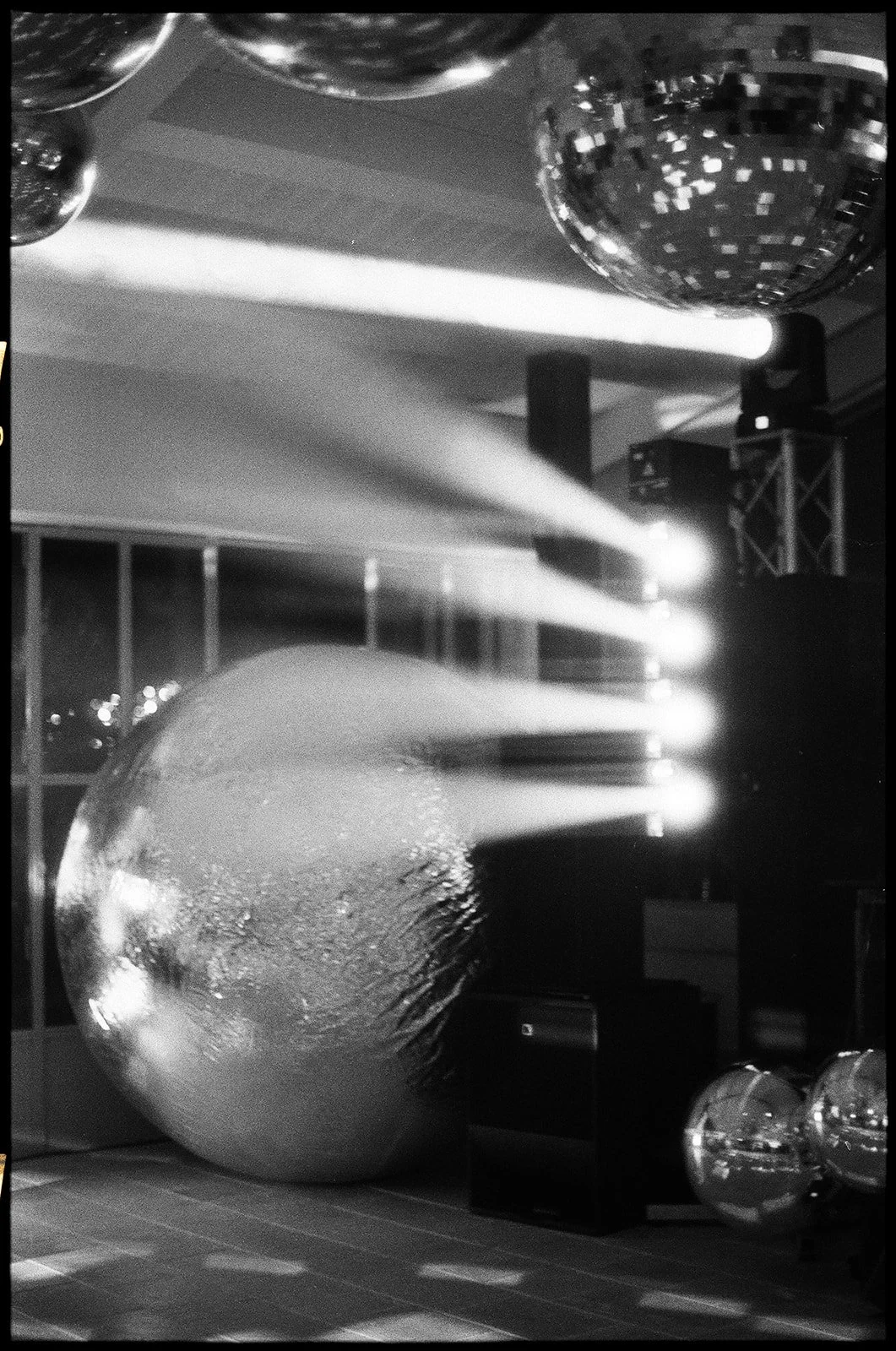 Large decorative disco ball with smaller disco balls and bright stage lighting at an indoor dance or event venue.