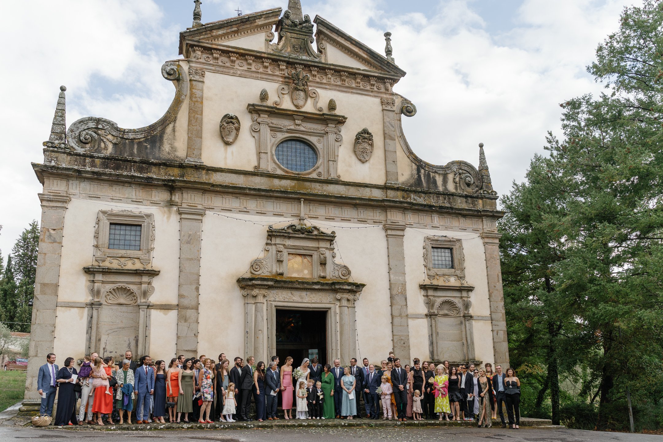Group of people gathered in front of a historic church building for a wedding celebration.