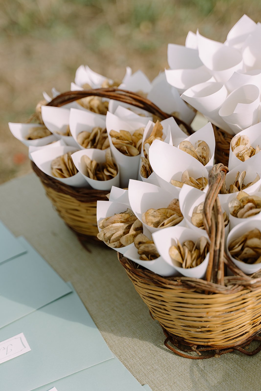 Basket filled with small paper cones containing food, likely nuts or snacks, arranged on a table covered with a light-colored cloth.
