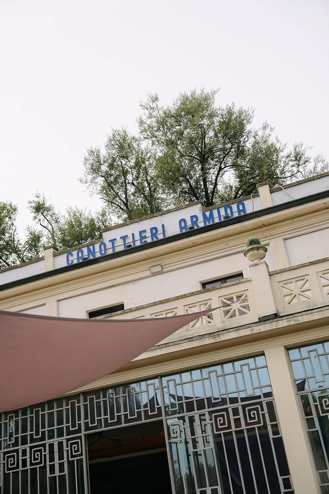 A building with a sign that reads 'Canottieri Armida' on the roof, and trees in the background.