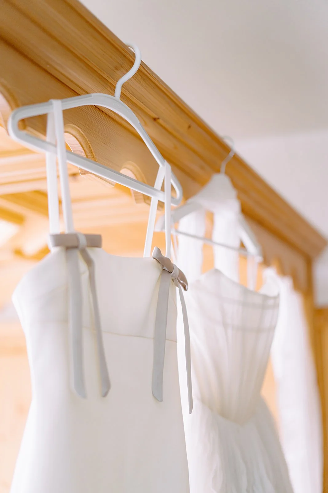 White wedding dress and veil hanging on a wooden rack in a closet.