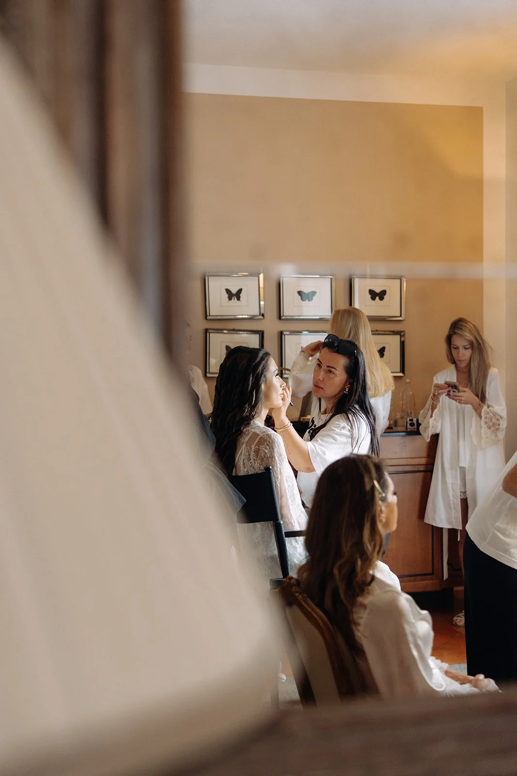 Women preparing for a special event, with butterfly artwork on the wall in the background.