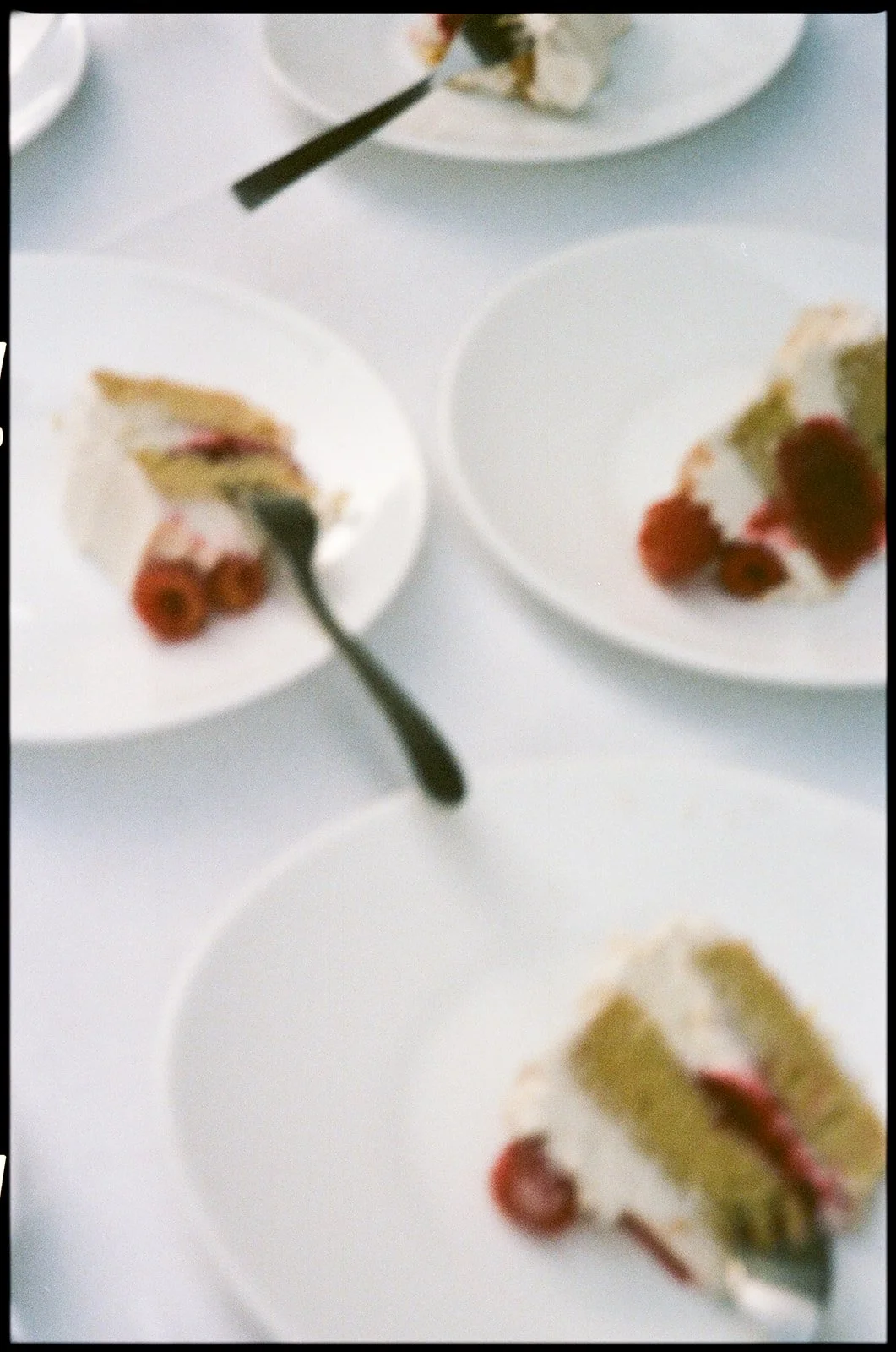 Multiple slices of cake on white plates, with one plate showing a fork placed on it.