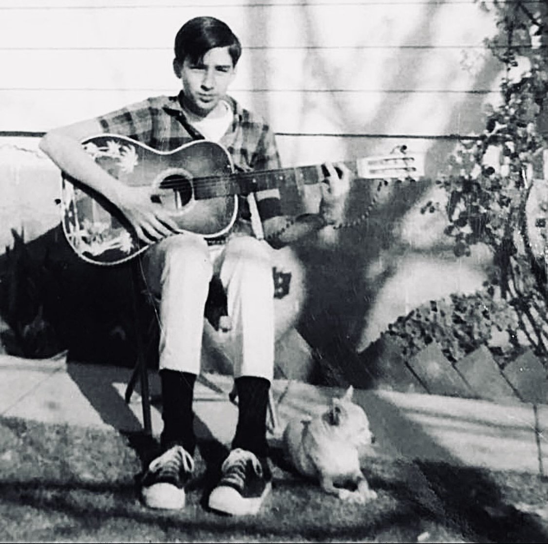 The author as a young boy playing a guitar, with his dog Pepe at his feet.