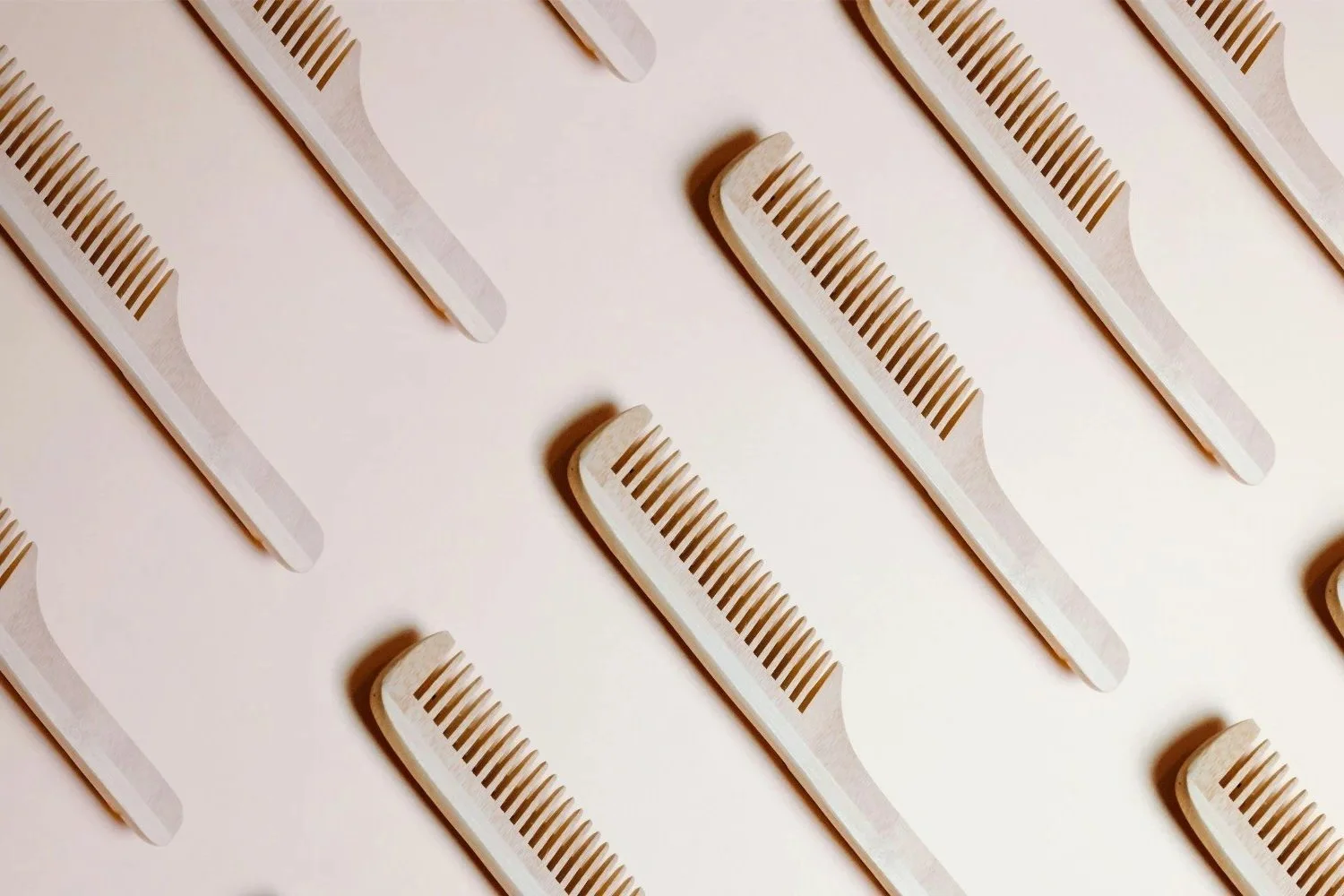 Multiple light-colored hair combs arranged diagonally on a white background.