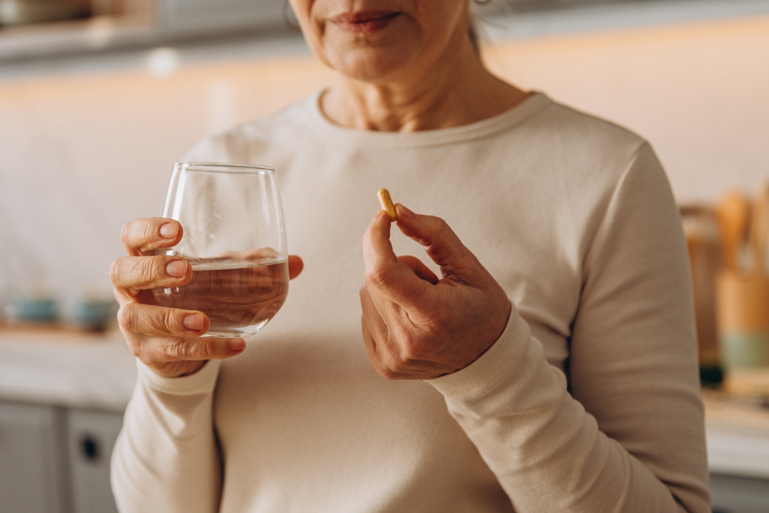 mature woman holds medical supplements for health care at home