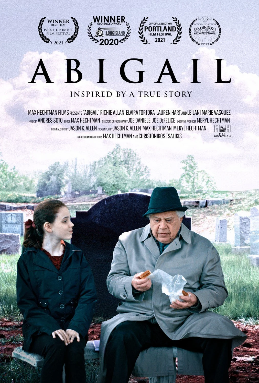 A young girl and an elderly man sit on a bench with a graveyard backdrop. The man examines a sandwich. The text above reads "Abigail" with award symbols.