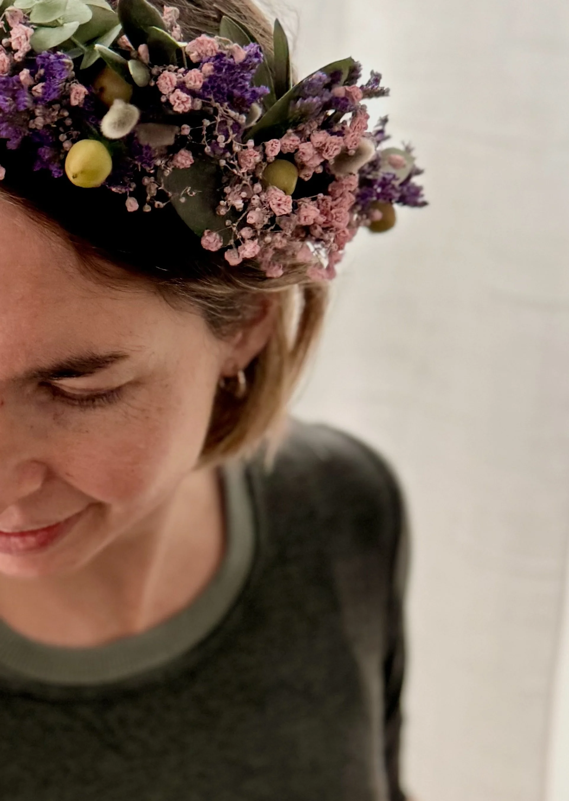 Man sieht das halbe Gesicht einer Frau, die ein Motherblessing bekommt und einen Blumenkranz in den Haaren trägt