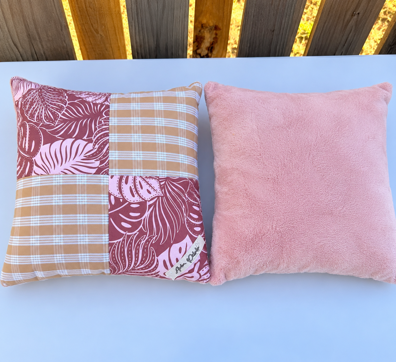Patchwork and Blush Pink Pillows by a Wooden Fence.png