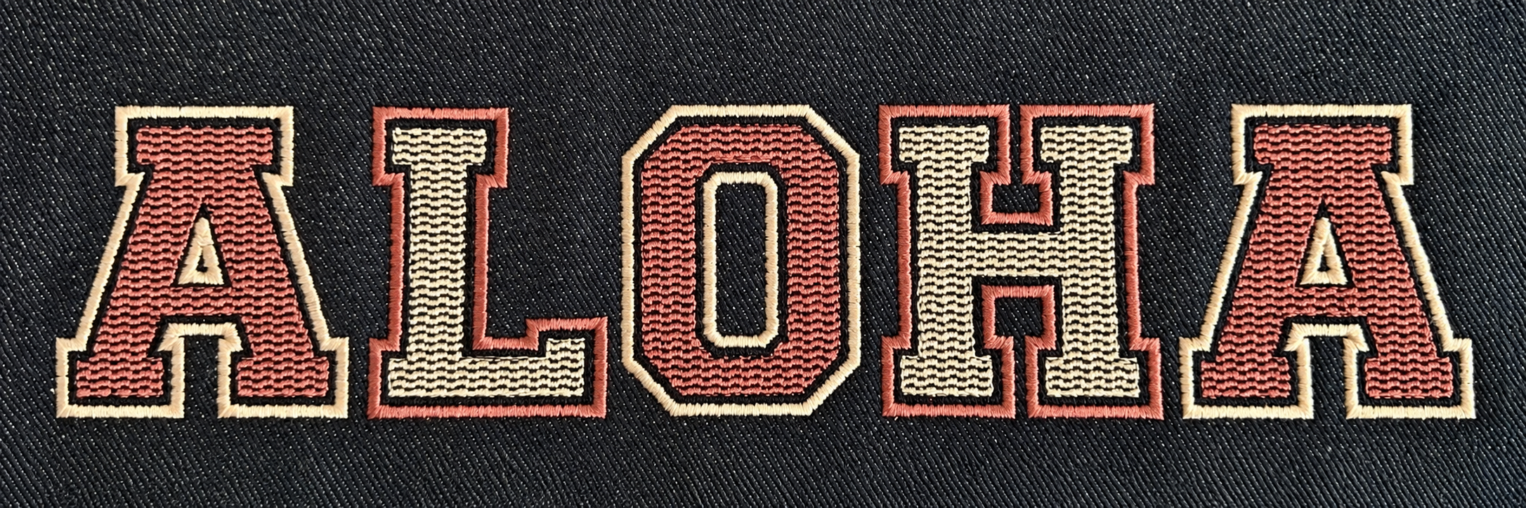 Cream and dusty rose ALOHA varsity embroidery stitched on black fabric.