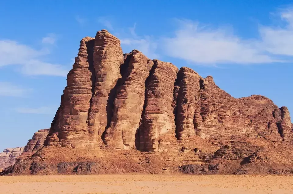 A large rock formation in a desert landscape with a clear blue sky overhead.