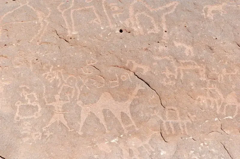 Ancient petroglyphs carved into a rock surface depicting human and animal figures.