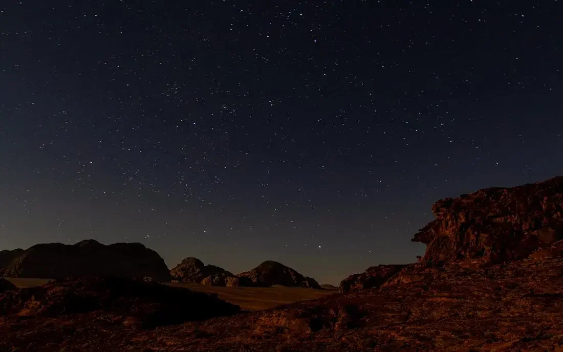 Night sky filled with stars over desert rocks