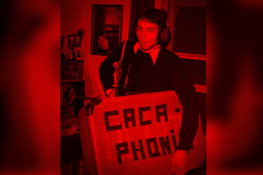 Een jongeman met koptelefoon die een bord vasthoudt met de tekst 'CACA-PHONI'.