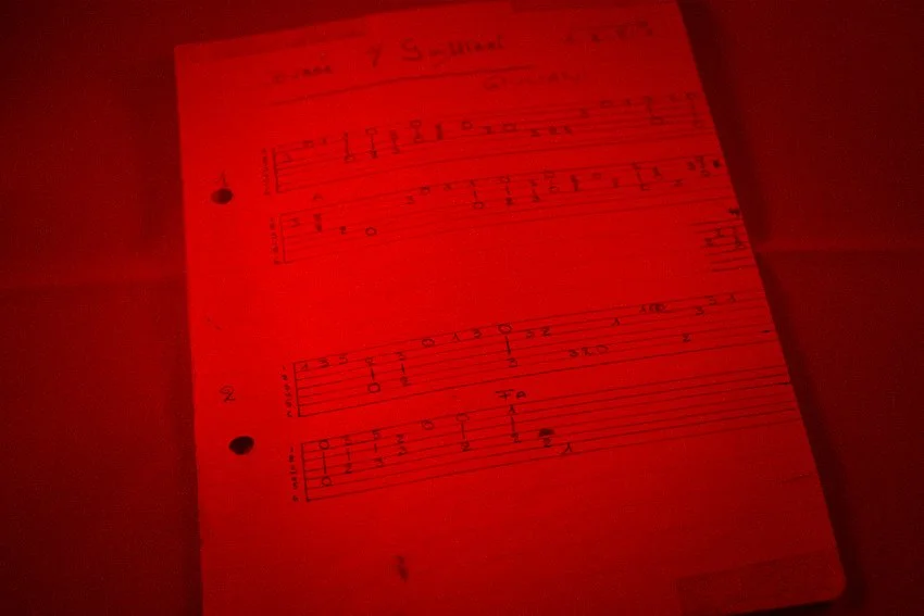 Blad met muzieknotities en tabulaturen, onder rood licht.